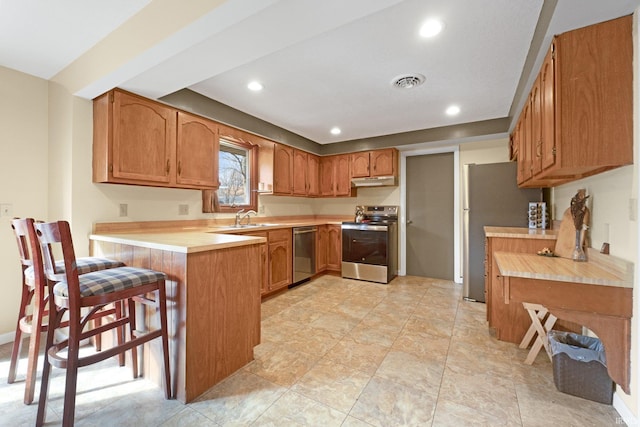 kitchen with sink, stainless steel appliances, kitchen peninsula, and a kitchen bar