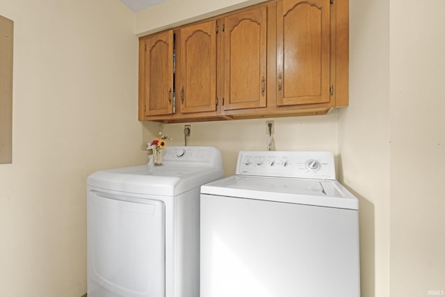 clothes washing area featuring cabinets and washer and dryer