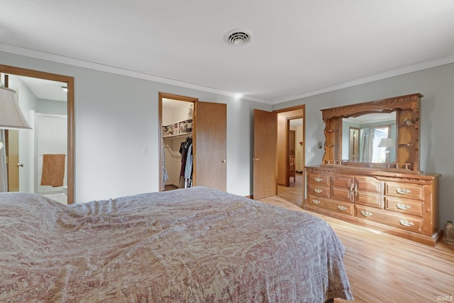 bedroom featuring crown molding, light hardwood / wood-style floors, and a spacious closet