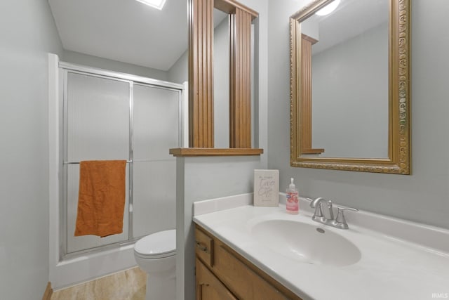 bathroom featuring vanity, a shower with door, and toilet