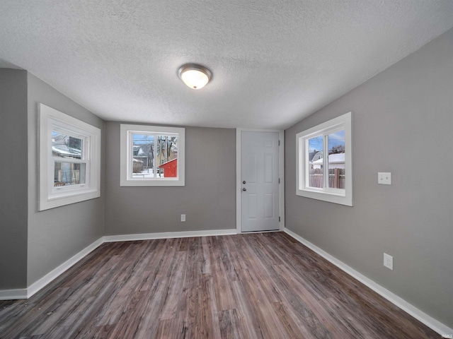 empty room with dark hardwood / wood-style floors and a textured ceiling