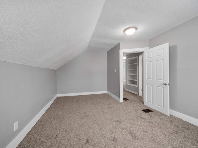 bonus room featuring light carpet, vaulted ceiling, and a textured ceiling