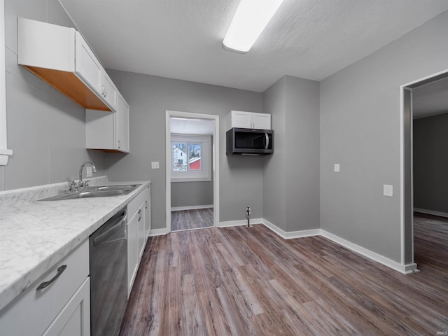 kitchen featuring appliances with stainless steel finishes, sink, wood-type flooring, and white cabinets