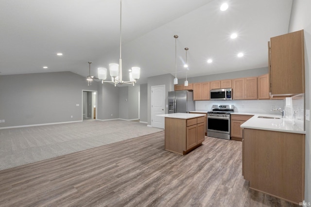 kitchen with lofted ceiling, sink, a kitchen island, pendant lighting, and stainless steel appliances