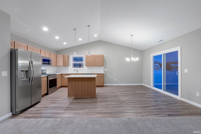 kitchen featuring appliances with stainless steel finishes, sink, hanging light fixtures, a center island, and a notable chandelier