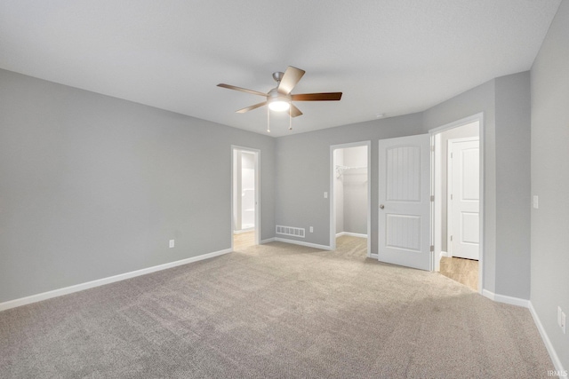 unfurnished bedroom featuring ceiling fan, light colored carpet, a spacious closet, and a closet