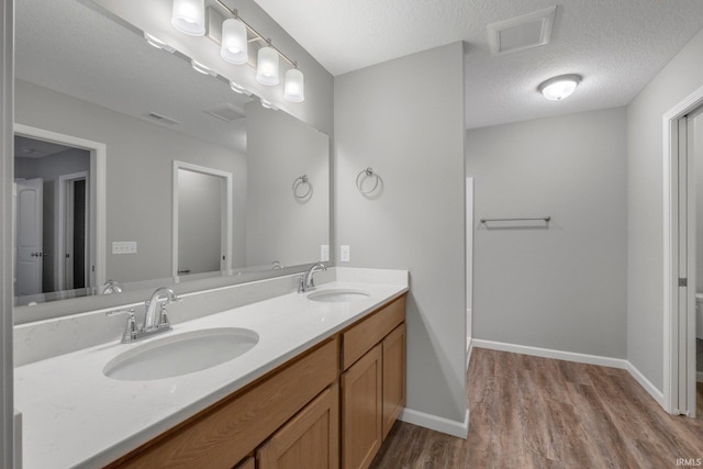 bathroom featuring wood-type flooring, vanity, a textured ceiling, and toilet