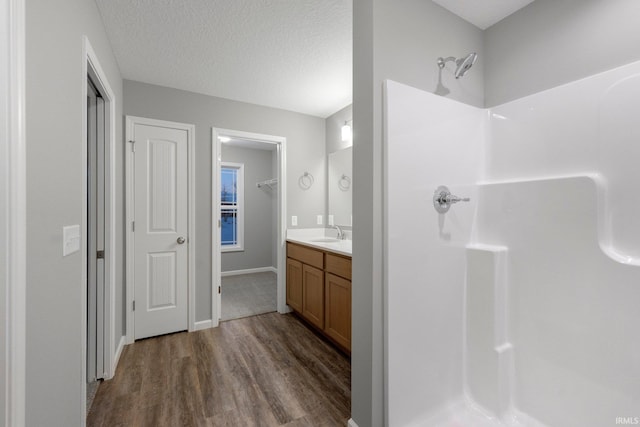 bathroom featuring vanity, a textured ceiling, wood-type flooring, and a shower