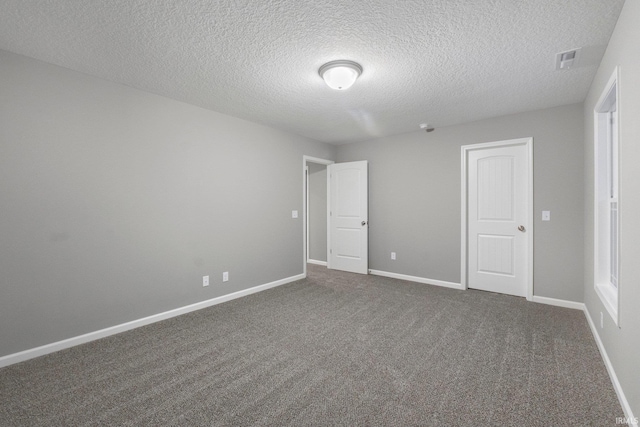 unfurnished room featuring a textured ceiling and dark carpet