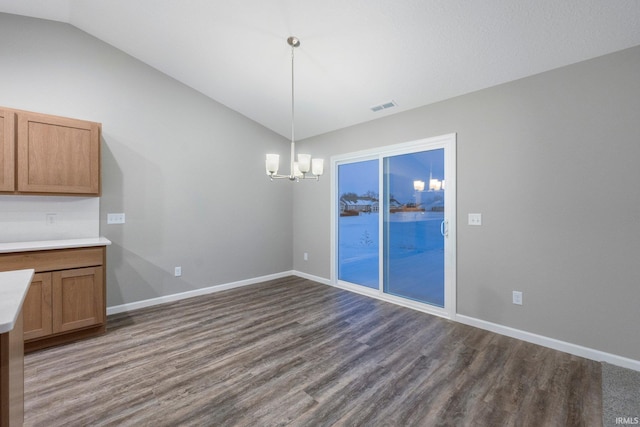 unfurnished dining area featuring dark hardwood / wood-style floors, vaulted ceiling, and a notable chandelier