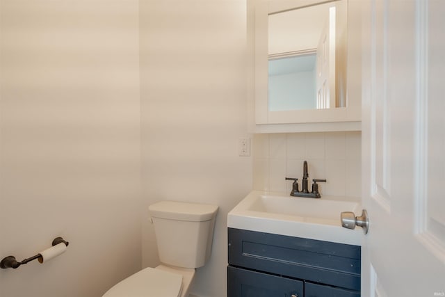 bathroom with vanity, toilet, and decorative backsplash