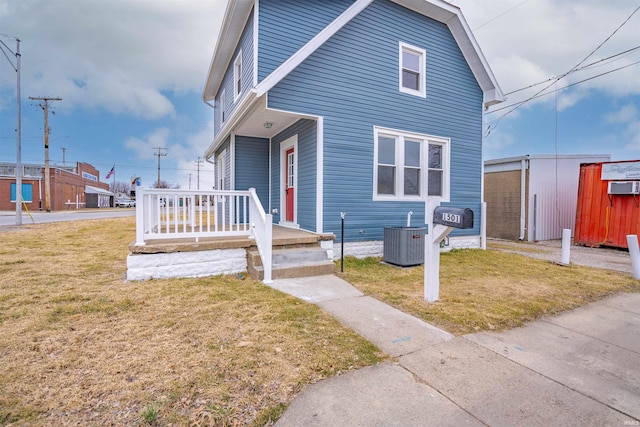 view of front of home with central AC unit, covered porch, and a front yard