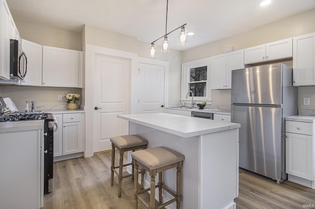 kitchen featuring appliances with stainless steel finishes, a kitchen breakfast bar, a kitchen island, pendant lighting, and white cabinets