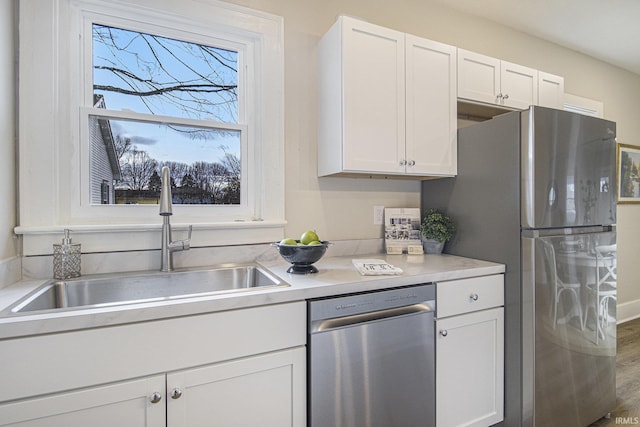 kitchen featuring hardwood / wood-style flooring, stainless steel appliances, sink, and white cabinets