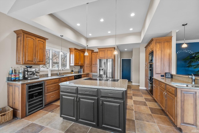 kitchen featuring a center island with sink, sink, pendant lighting, and black appliances