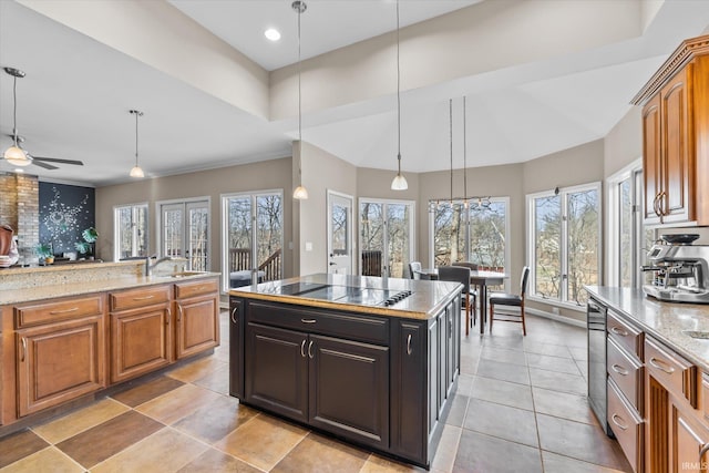 kitchen featuring sink, decorative light fixtures, black electric cooktop, a kitchen island, and light stone countertops