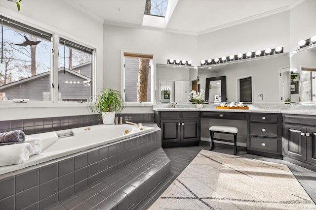 bathroom featuring crown molding, vanity, a skylight, and tiled tub