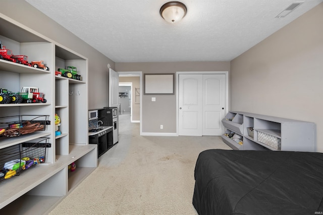 bedroom with light colored carpet, a textured ceiling, and a closet