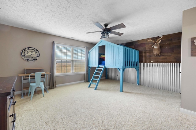 bedroom with ceiling fan, carpet floors, a textured ceiling, and wood walls