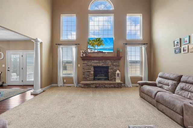 carpeted living room with a towering ceiling, a fireplace, and ornate columns