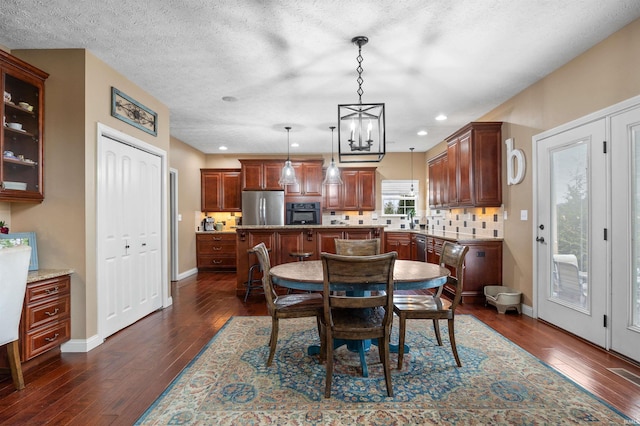 dining area with an inviting chandelier, dark hardwood / wood-style floors, and a textured ceiling