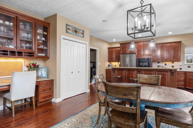 dining room featuring dark wood-type flooring, built in desk, and a textured ceiling