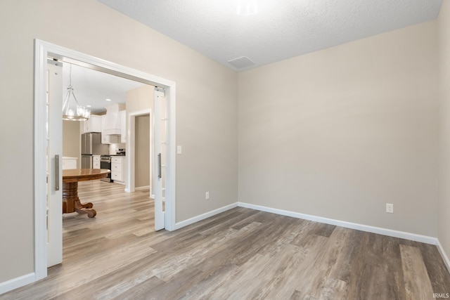 unfurnished room with light hardwood / wood-style flooring and a textured ceiling