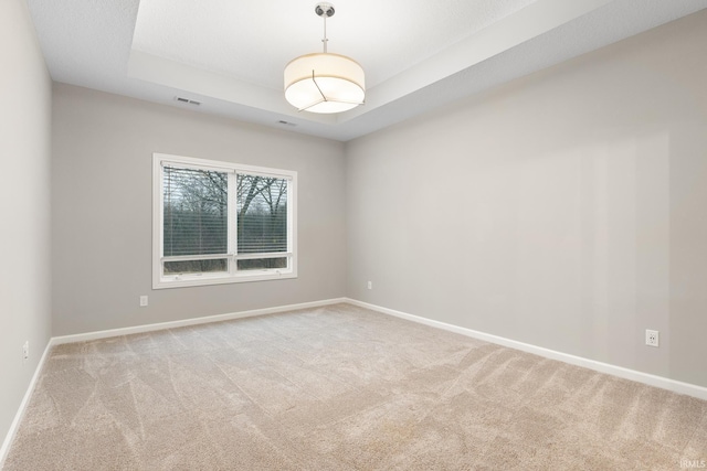 carpeted spare room with a tray ceiling