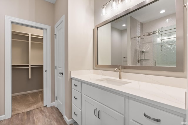 bathroom with a shower with door, vanity, and hardwood / wood-style flooring