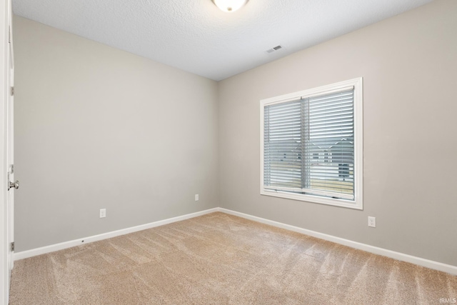 carpeted empty room with a textured ceiling