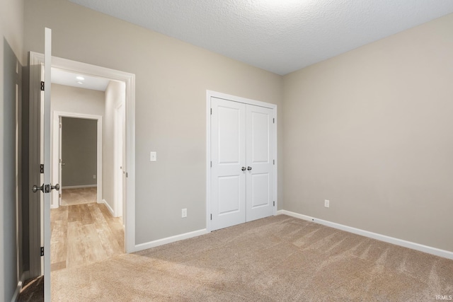 unfurnished bedroom featuring light colored carpet, a closet, and a textured ceiling