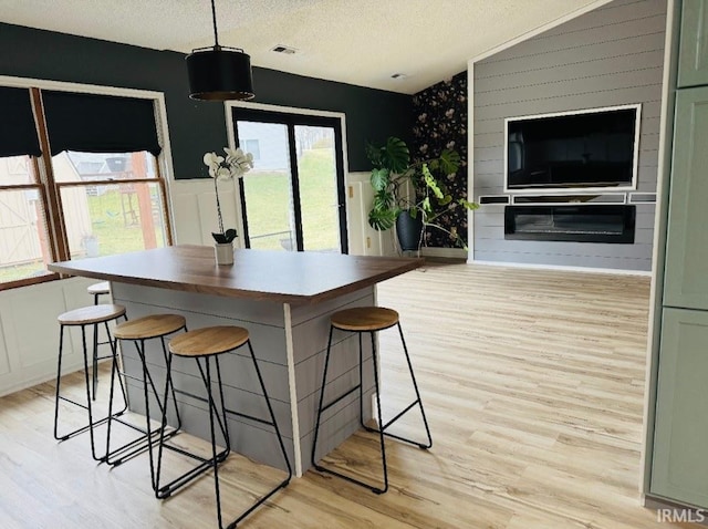 kitchen featuring hanging light fixtures, a breakfast bar, a textured ceiling, and light hardwood / wood-style floors