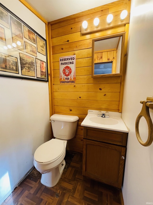 bathroom featuring vanity, parquet flooring, toilet, and wood walls