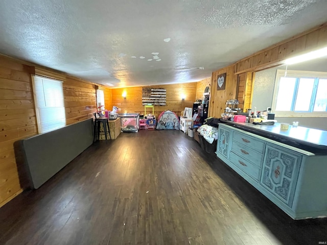 misc room with dark wood-type flooring, wooden walls, and a textured ceiling