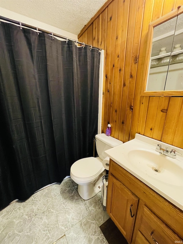 bathroom with wooden walls, vanity, a textured ceiling, toilet, and walk in shower