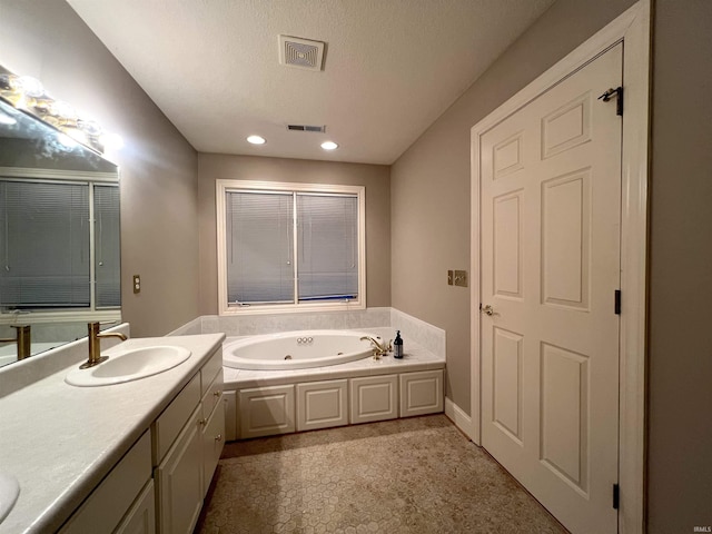 bathroom with vanity, a textured ceiling, and a washtub