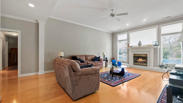 living room with crown molding, ceiling fan, decorative columns, and light wood-type flooring