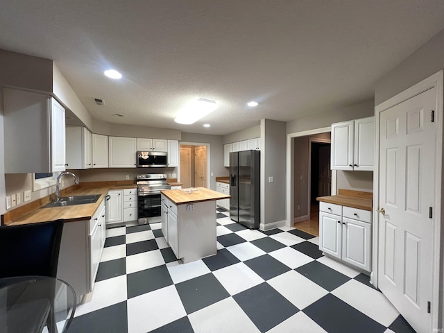 kitchen featuring white cabinetry, wood counters, and appliances with stainless steel finishes