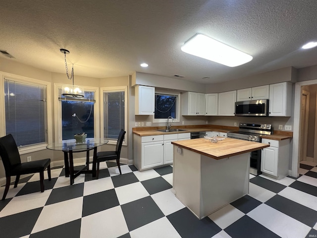 kitchen with sink, wooden counters, stainless steel appliances, white cabinets, and a kitchen island