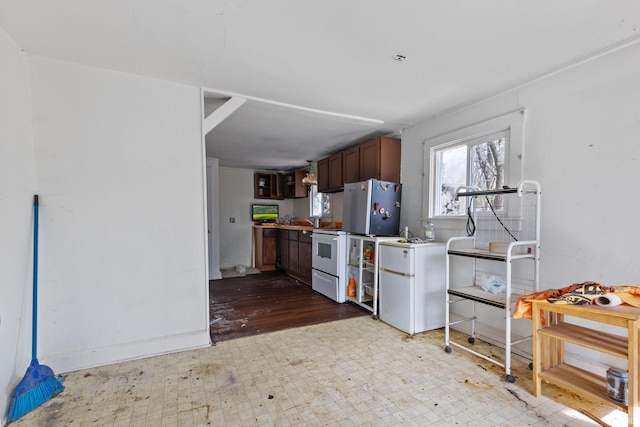 kitchen featuring electric stove, dark brown cabinets, stainless steel fridge, and fridge