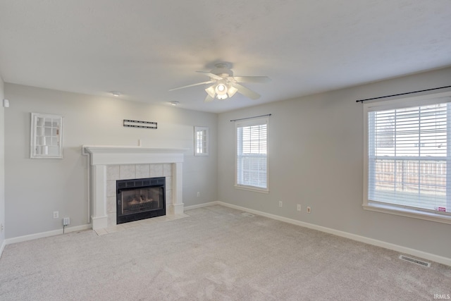 unfurnished living room featuring ceiling fan, light carpet, and a tile fireplace