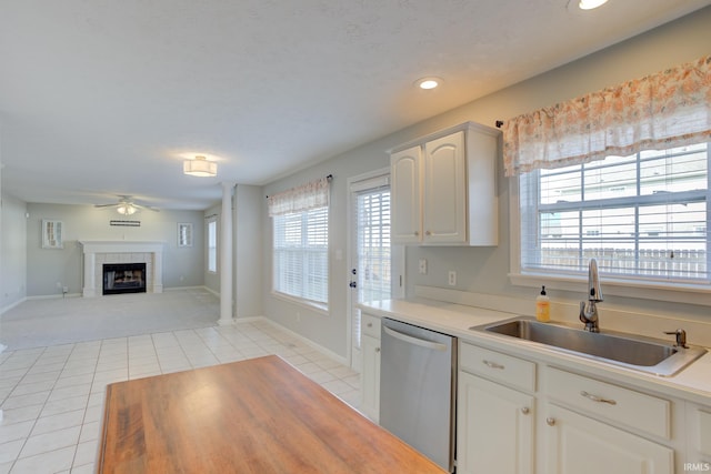 kitchen featuring white cabinetry, dishwasher, sink, a tiled fireplace, and light tile patterned floors