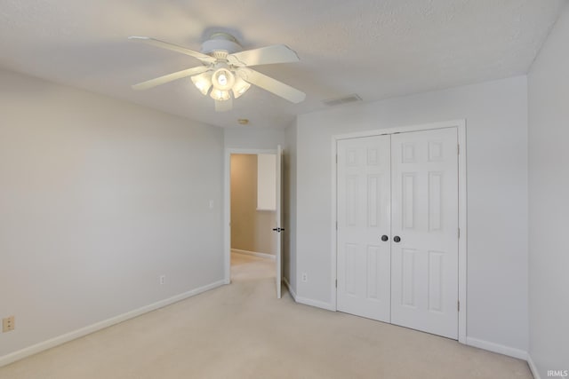 unfurnished bedroom featuring a textured ceiling, light colored carpet, a closet, and ceiling fan