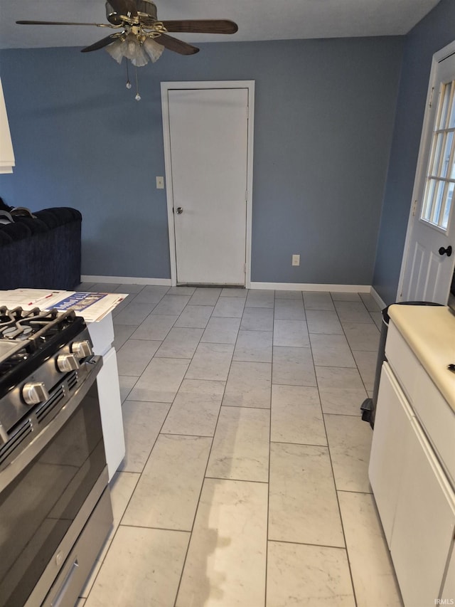 kitchen featuring white cabinetry, light tile patterned floors, stainless steel range with gas cooktop, ceiling fan, and stove