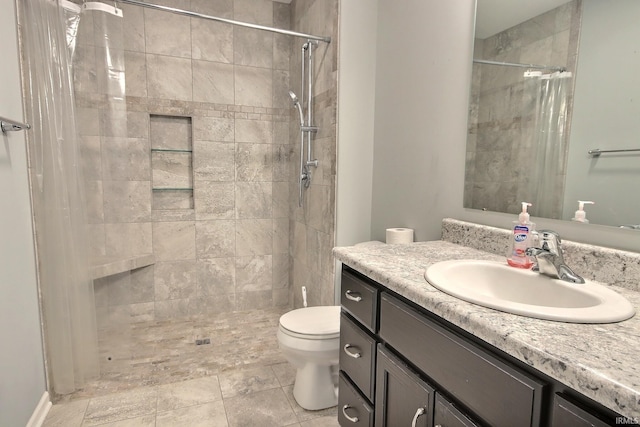 bathroom with vanity, toilet, and a tile shower