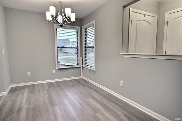 empty room with an inviting chandelier and hardwood / wood-style floors