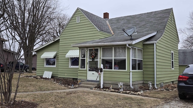 view of front of home with entry steps, roof with shingles, and a chimney