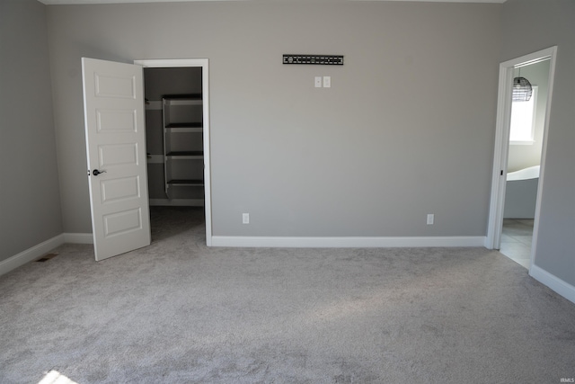 unfurnished bedroom with light colored carpet, a closet, and a walk in closet