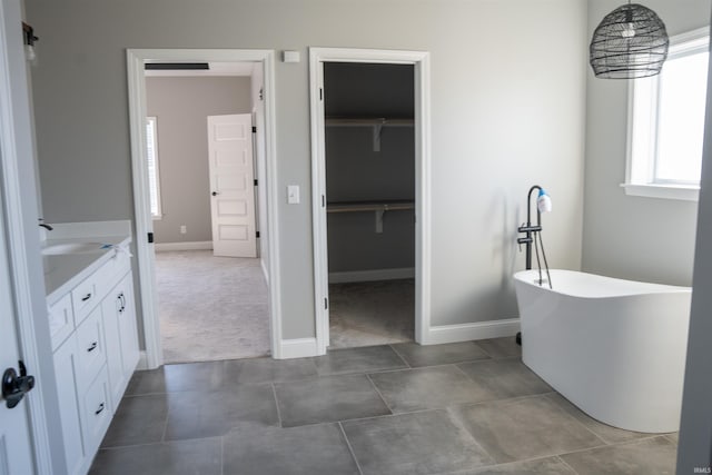 bathroom featuring vanity, a washtub, and tile patterned floors