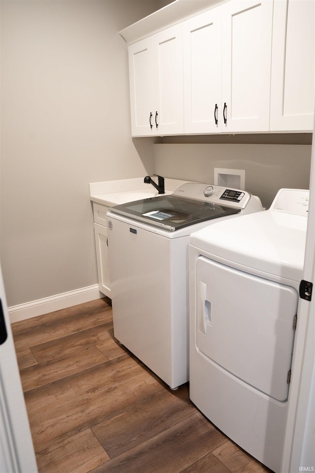 clothes washing area featuring separate washer and dryer, dark hardwood / wood-style flooring, and cabinets